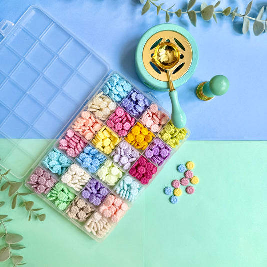 Pastel coloured flower-shaped sealing wax beads in a storage box