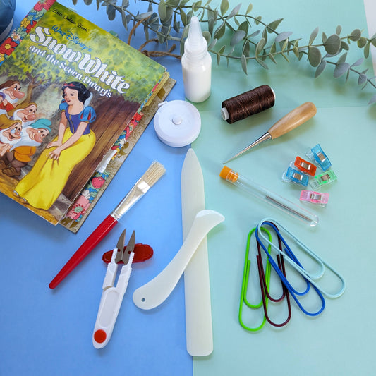 Crafting tools for handmade journals displayed with a handmade journal in background