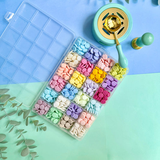 Pastel coloured flower-shaped sealing wax beads in a storage box