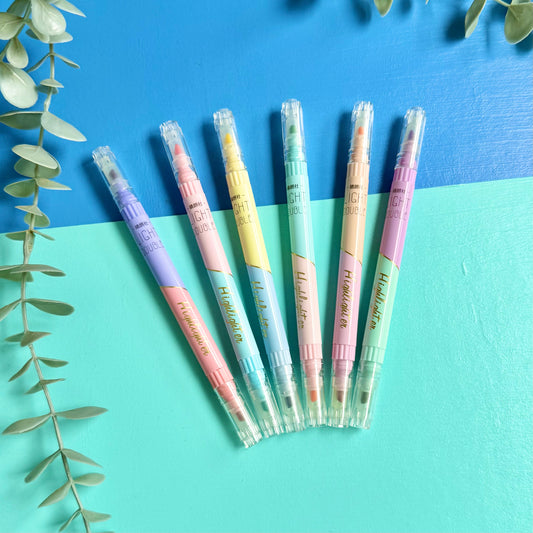 Set of 6 pastel double-ended highlighters fanned out on a blue and teal background