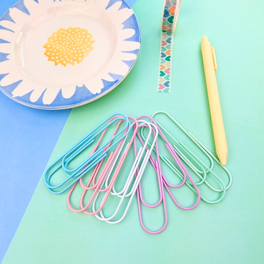Colorful paper clips on a colorful background with a plate and pen.